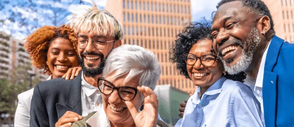 A group of smiling friends of different ages standing together outdoors