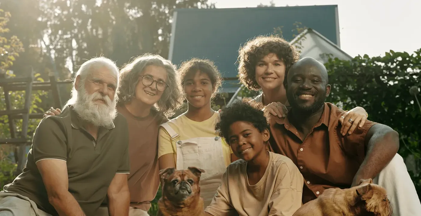 Three generations of a family sitting together on their lawn with their dogs