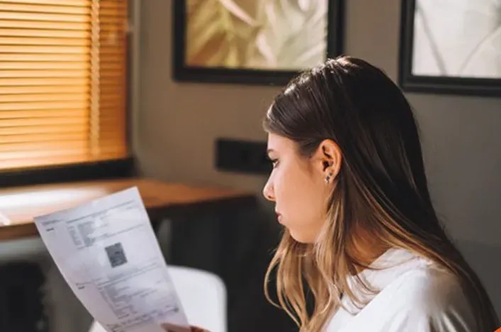 A young woman reading a letter at her desk