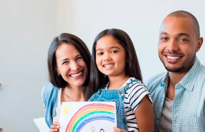 Smiling parents with their daughter holding a drawing of a family