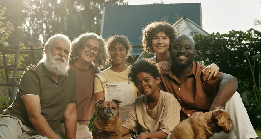 Three generations of a family sitting together on the lawn with their dogs
